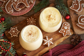 Two glasses of homemade eggnog with gingerbread cookies and Christmas tree branches