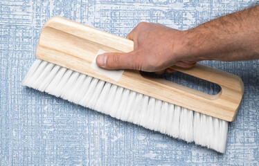 A hand skillfully using a brush to create a beautiful textured wall painting design