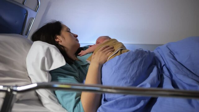 Video of newborn baby sleeping on mother's chest in hospital bed after delivery