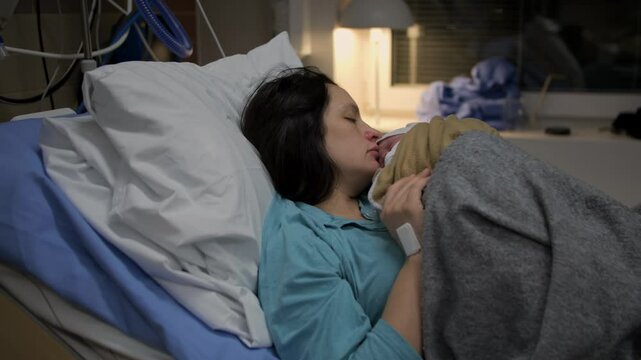 Video of mother and newborn baby resting and recovering, sleeping in dark room after childbirth