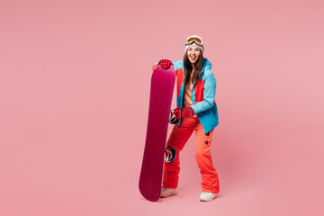 Full body young happy woman wear warm blue padded jacket ski goggles mask spend weekend winter...