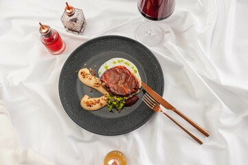 Braised Pork Steak with Parsnip Cream on a Black Plate