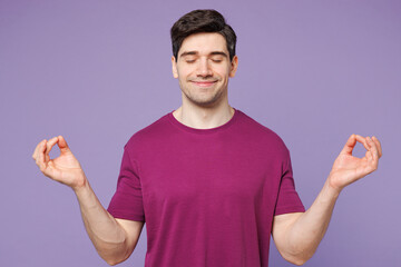 Young Caucasian man wear violet t-shirt casual clothes hold spreading hands in yoga om aum gesture relax meditate try to calm down isolated on plain pastel light purple background. Lifestyle concept.