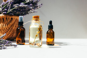 Lavender oil on light background with lavender flowers in a bright sunlight. Front view