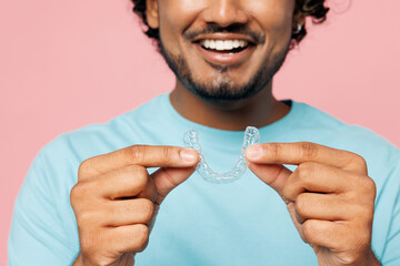 Cropped young smiling Indian man he wear blue t-shirt casual clothes hold in hand invisible...