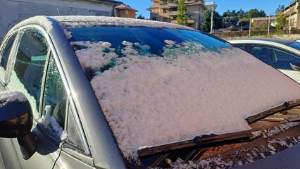 Primo piano della neve sull'auto. Auto sporca ricoperta da un sottile strato di neve sul parabrezza anteriore.
