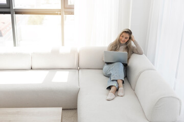 Fototapeta premium happy young businesswoman with laptop on comfortable sofa 