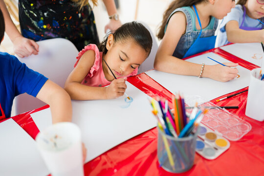 Elementary school art class: young students focused on watercolor painting and using colored pencils