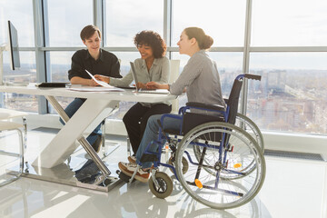 Teamwork brainstorm. Diverse multiracial colleagues woman in chair for people with disability...