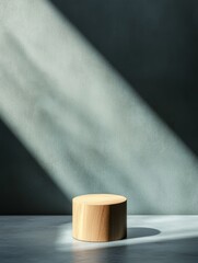 Fototapeta premium A minimalist wooden cylinder sits on a surface, illuminated by soft, dramatic lighting against a textured background.