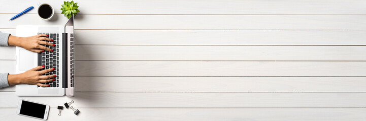Female hands working on modern laptop. White wooden office desktop