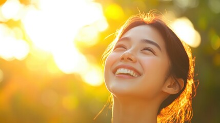 A natural, candid shot of a mixed-heritage Asian woman laughing, her face glowing in the sunlight as her joyful expression captures a moment of pure happiness