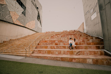 Young couple sitting together on steps at Federation Square