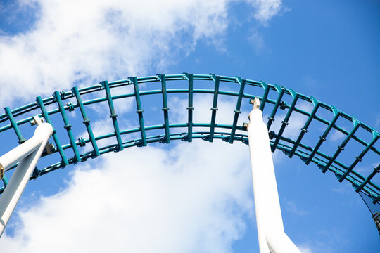 looking up at roller coaster tracks against a blue sky