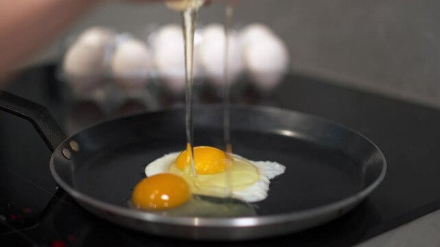 This is a closeup image of a perfectly frying egg on a hot skillet with several eggs visible in the background