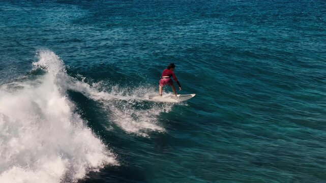 Teen boy surfer rides the wave in the Maldives