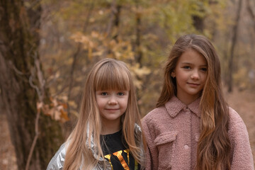 Portrait of two little girls standing next to each other in a park