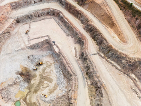 Aerial view looking down into a quarry pit with machinery on the ground
