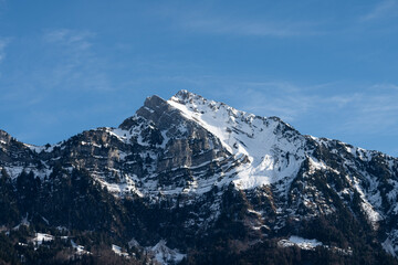 Fototapeta premium A majestic snow-capped mountain peak rises triumphantly into the clear blue sky, embodying nature’s majestic beauty and the grandeur of the wilderness.