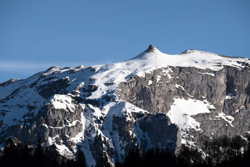 A breathtaking snowy peak stands majestically beneath a clear azure sky, epitomizing the serene...