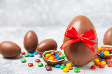 Obraz premium Easter chocolate egg on textured background. Easter celebration concept. Easter chocolate rabbit. Chocolate sweet eggs. Candies on textured wooden table. Space for text.Copy space. Gift. Banner.