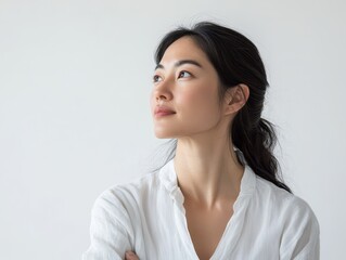 Obraz premium Thoughtful Asian woman looking into the distance, pure white backdrop, capturing strength through introspection and calm