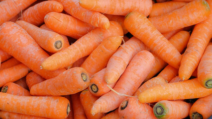 Background pattern and texture of a pile of orange carrots.Pile of carrots at the market. Source of vitamin A for eye health. Natural pattern and texture background. Can be used for graphic design 