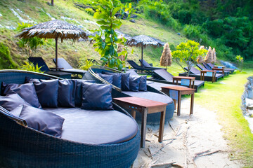Round sun loungers on the beach area of the hotel by the sea. Sun loungers by the pool with tables and umbrellas.