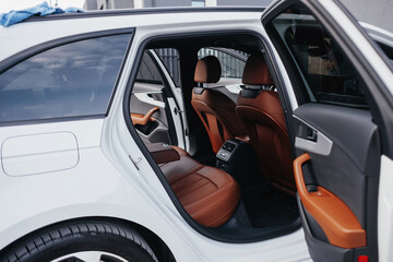 Modern brown car interior, leather steering wheel, climate control, navigation, air ducts, deflectors on the car panel, interior details.