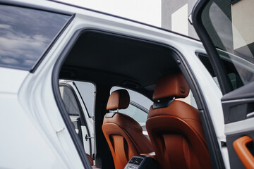 Fototapeta premium Modern brown car interior, leather steering wheel, climate control, navigation, air ducts, deflectors on the car panel, interior details.