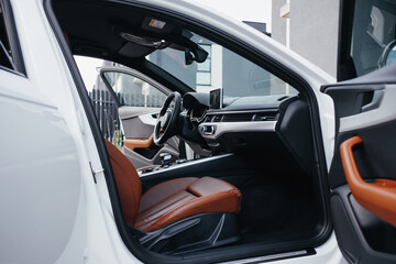 Modern brown car interior, leather steering wheel, climate control, navigation, air ducts, deflectors on the car panel, interior details.