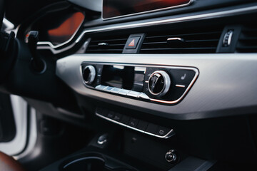 Modern brown car interior, leather steering wheel, climate control, navigation, air ducts, deflectors on the car panel, interior details.