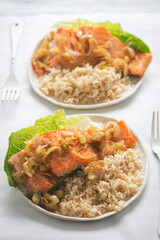 Salmon in shallot ginger soy sauce with brown rice served on romaine lettuce 