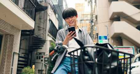 Naklejka premium Phone, bicycle and smile with Japanese man in city for location, digital map and travel. Social media, cycling and mobile app with person and bike in japan for networking, connection and adventure