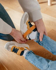 Dad slowly puts on and takes off the child's shoes slowly on a white sock in a room at home on a...