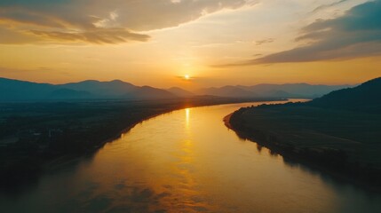 Fototapeta premium Sunset over the Mekong River in Nong Khai, Thailand, with mountains and green countryside framing the serene waters. The sky is ablaze with warm colors, creating a mesmerizing view.