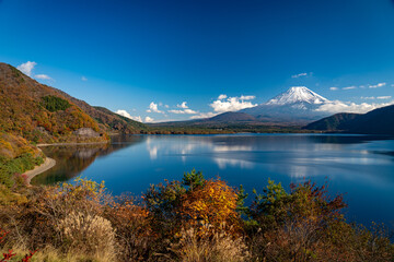 紅葉に囲まれた湖越しに望む冠雪した富士山