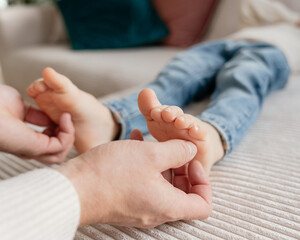 A dad holds his 4-year-old son's feet and tickles them.