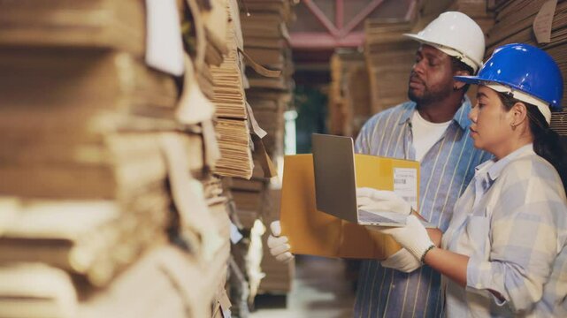 African man worker and asian woman recheck stock at paper factory.