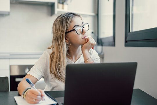 Portrait of serious millennial caucasian female student sit at desk at home study online on laptop. Thoughtful young attractive woman use computer take distant course or training. Education concept..