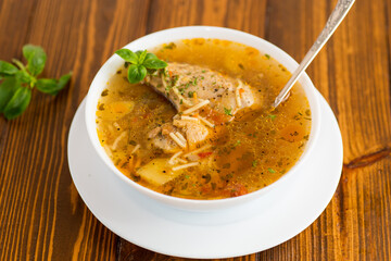 hot cooked chicken and noodle soup in a plate on a wooden table