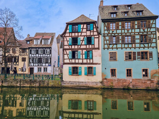 Obraz premium Picturesque river view in La Petite France in Strasbourg with half-timbered houses and water reflection, Colourful architecture, canal and blue sky in November, Travel destination, Alsace, France