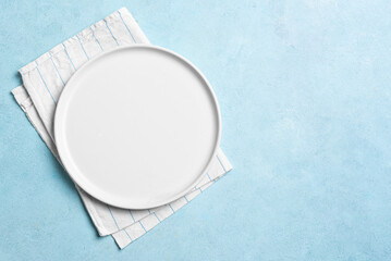 Empty white plate and napkin on blue background