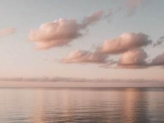 Soft pastel sunset with gentle clouds over still ocean waters.