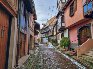 Eguisheim with Christmas decoration - Charming, colorful, snowy cobblestone street with half-timbered houses in snow and colorful facades, France's most beautiful village, Alsace region, France