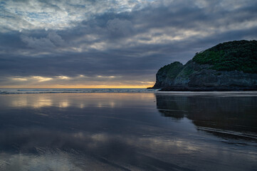 Sunset clouds reflections at the Te Henga surf beach, Auckland, New Zealand