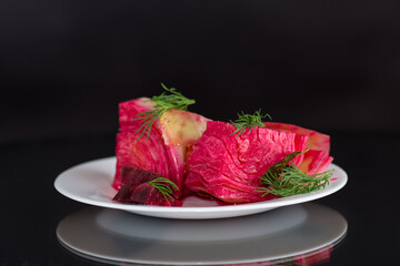 pickled cabbage with beets and carrots, in a plate, isolated on black background