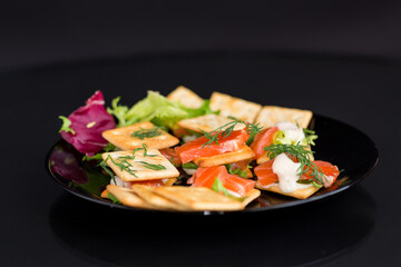 small snack canapes with crackers and lightly salted red fish Salmon, isolated on black background