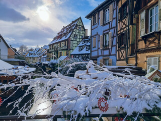 Picturesque view on Colmar street with snow. Half-timbered houses, Colourful architecture, canal and blue sky. Travel destination, Christmas decoration in Colmar, Alsace, France