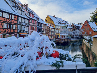 Picturesque view with Christmas decoration to La Petite Venise with snow on half-timbered houses, Colourful architecture, canal and blue sky. Travel destination, Colmar, Alsace, France